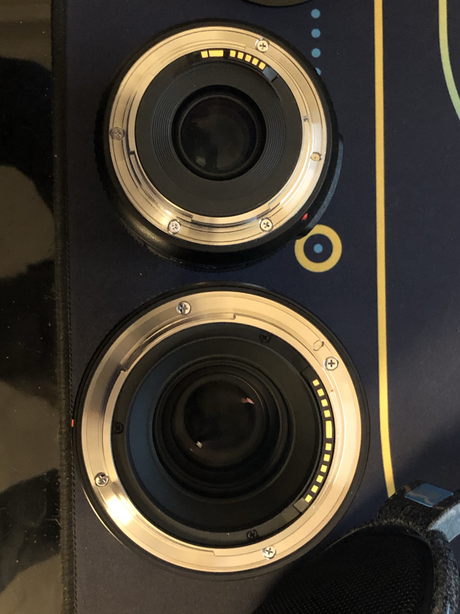 Two lenses on table showing the bayonet mount, smaller first lens has 7 visible contacts, the second has 11