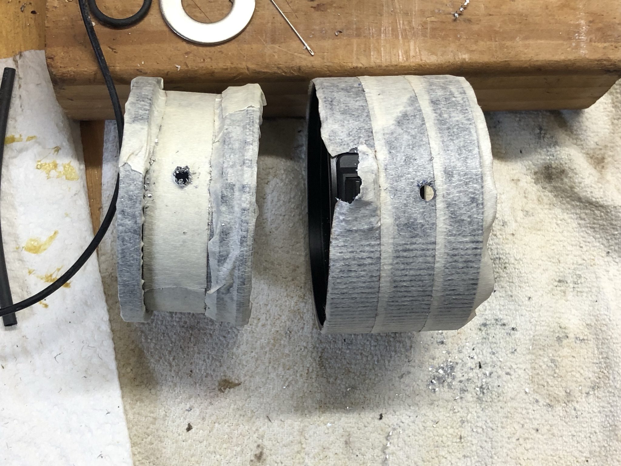 Metal tube sections wrapped in masking tape, holes drilled in sides